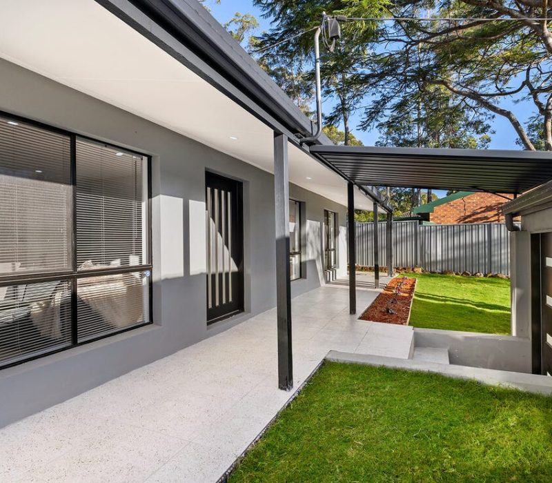 Contemporary grey home facade with landscaped lawn and walkway