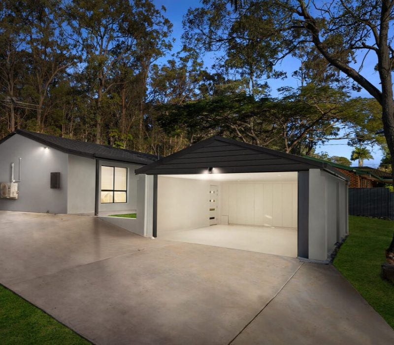 Modern grey home with wide driveway and double garage at dusk