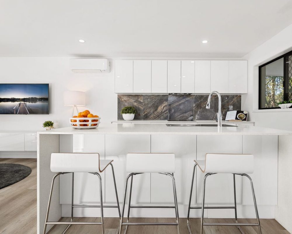 Modern white kitchen with island bench and stone splashback