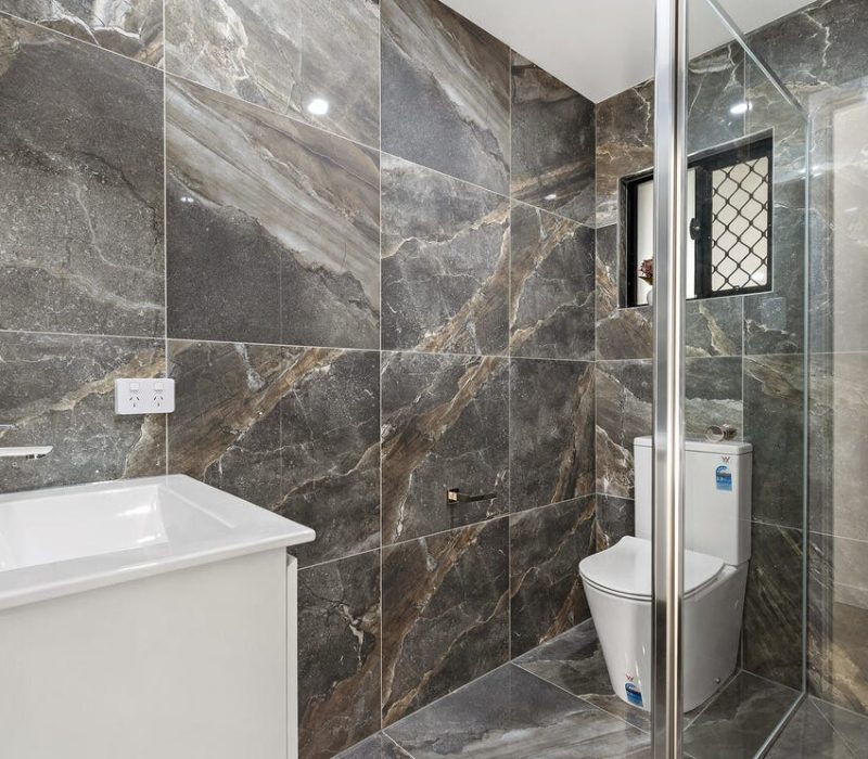 Stone-look tiled bathroom with white vanity and toilet