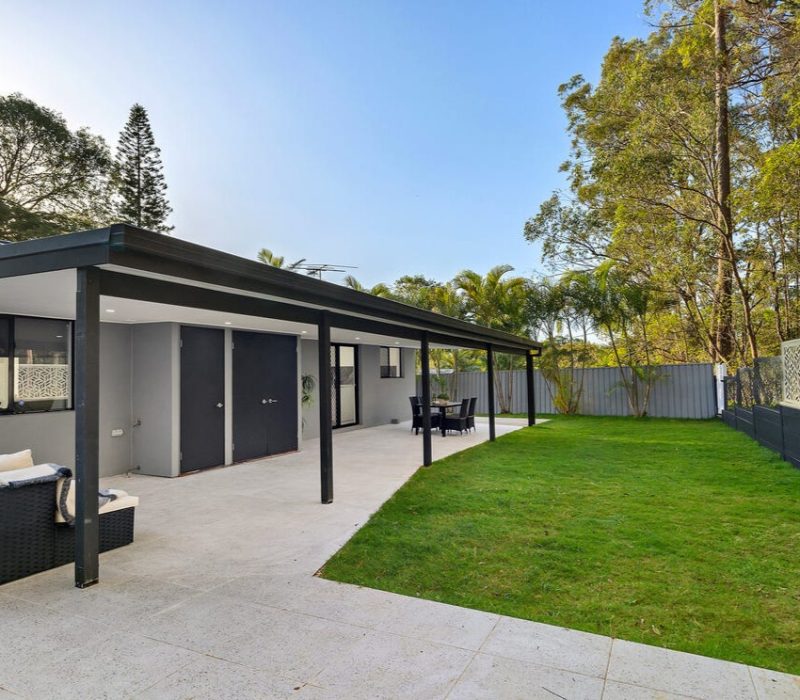 Backyard patio area with green grass and privacy fencing