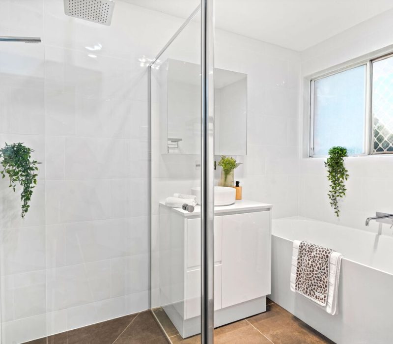 White tiled bathroom with shower, bath, and large window