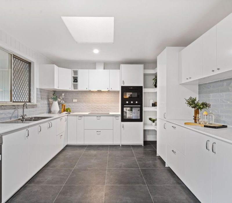 Spacious kitchen with white cabinetry and soft blue splashback tiles