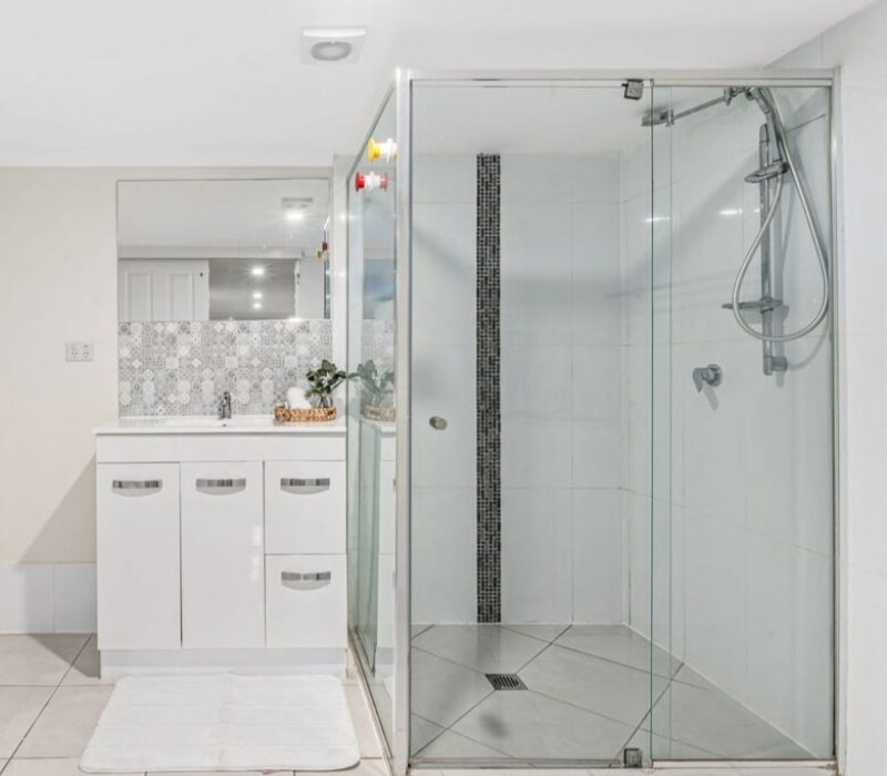 White vanity with feature tile splashback and walk-in glass shower