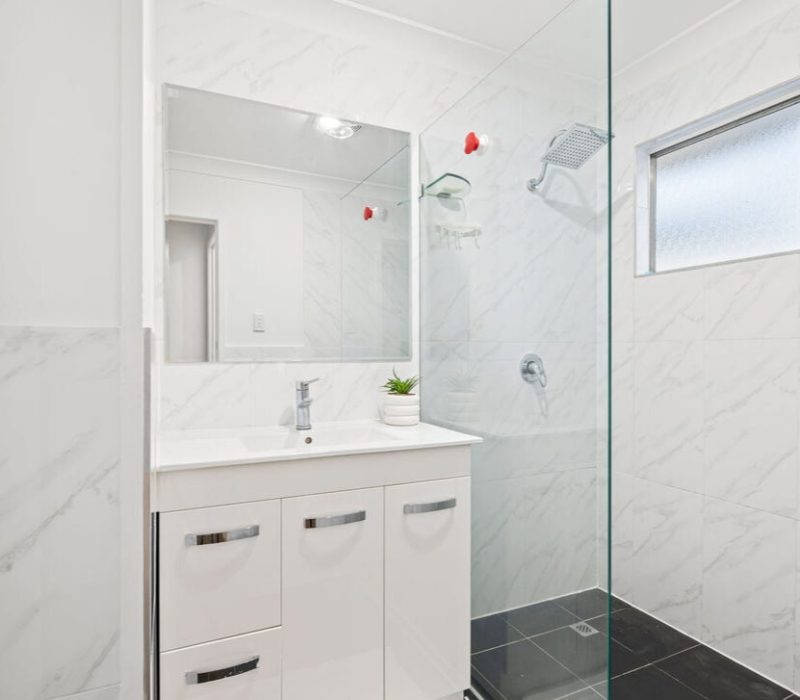 Shower with white marble-look tiles and floating vanity