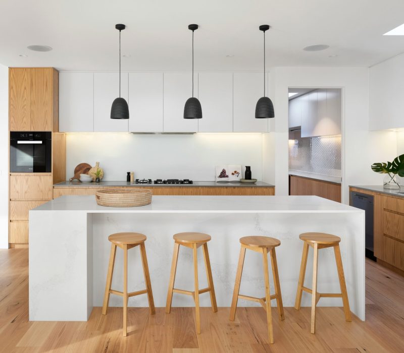 Modern kitchen with timber cabinetry, black tapware and white stone benchtops